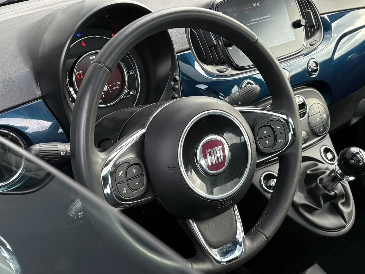 Vue intérieure centrée sur le volant noir et la console bleu Dipinto avec levier de vitesses manuel de la Fiat 500 Hybrid 2024.