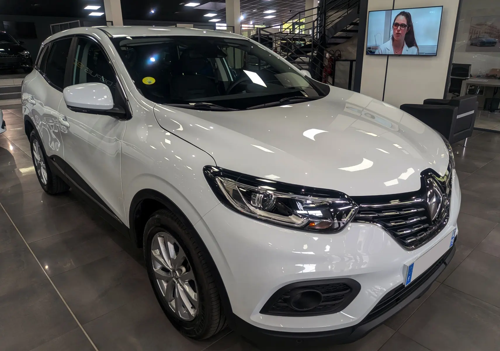 Renault Kadjar blanc Glacier en 3/4 avant droit, avec calandre chromée et phares LED visibles en showroom.
