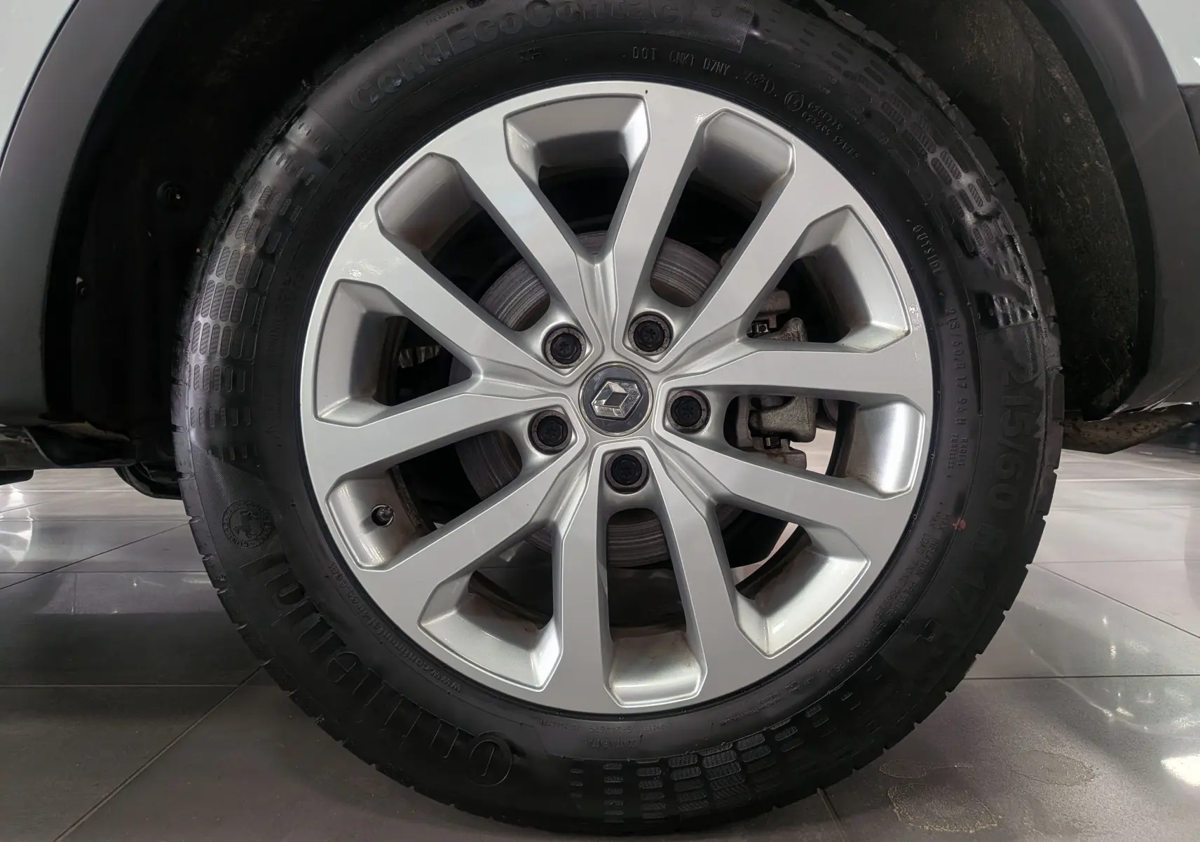 Gros plan sur la jante alliage argentée avec logo Renault au centre, montée sur un pneu Continental du Renault Kadjar blanc.