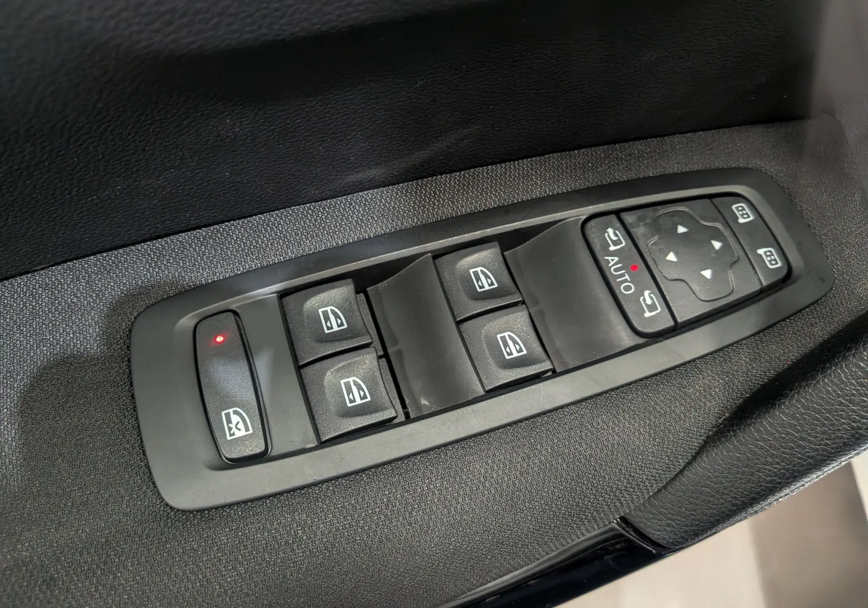 Panneau de commandes des vitres et rétroviseurs électriques sur la porte côté gauche d’un Renault Kadjar blanc Glacier.