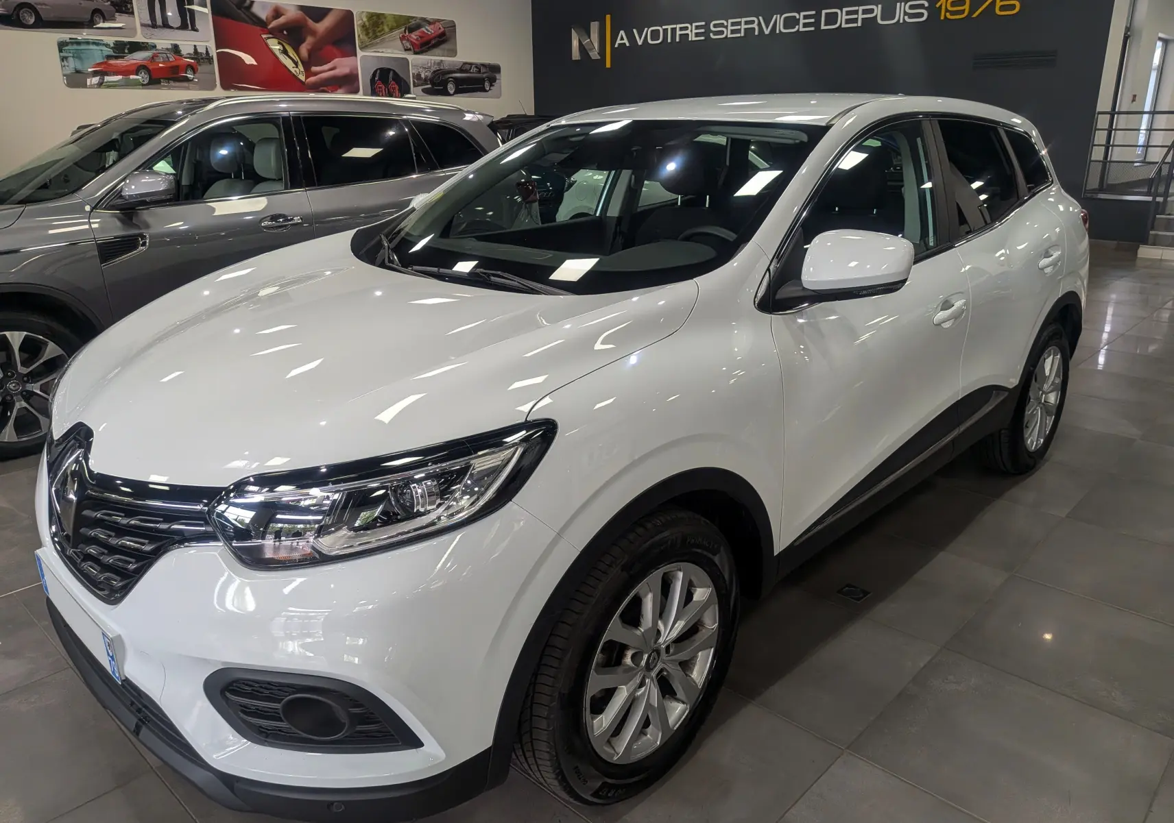Renault Kadjar Blanc Glacier en vue 3/4 avant droit, avec jantes alliage et calandre chromée visible en showroom.