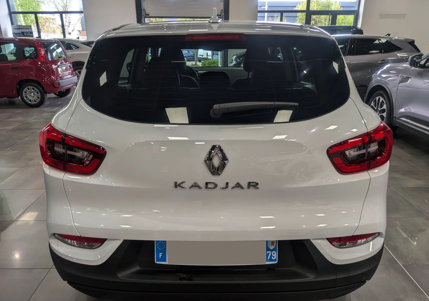 Vue arrière d'un Renault Kadjar blanc Glacier 2021 en showroom, avec feux arrière LED et logo central visible.