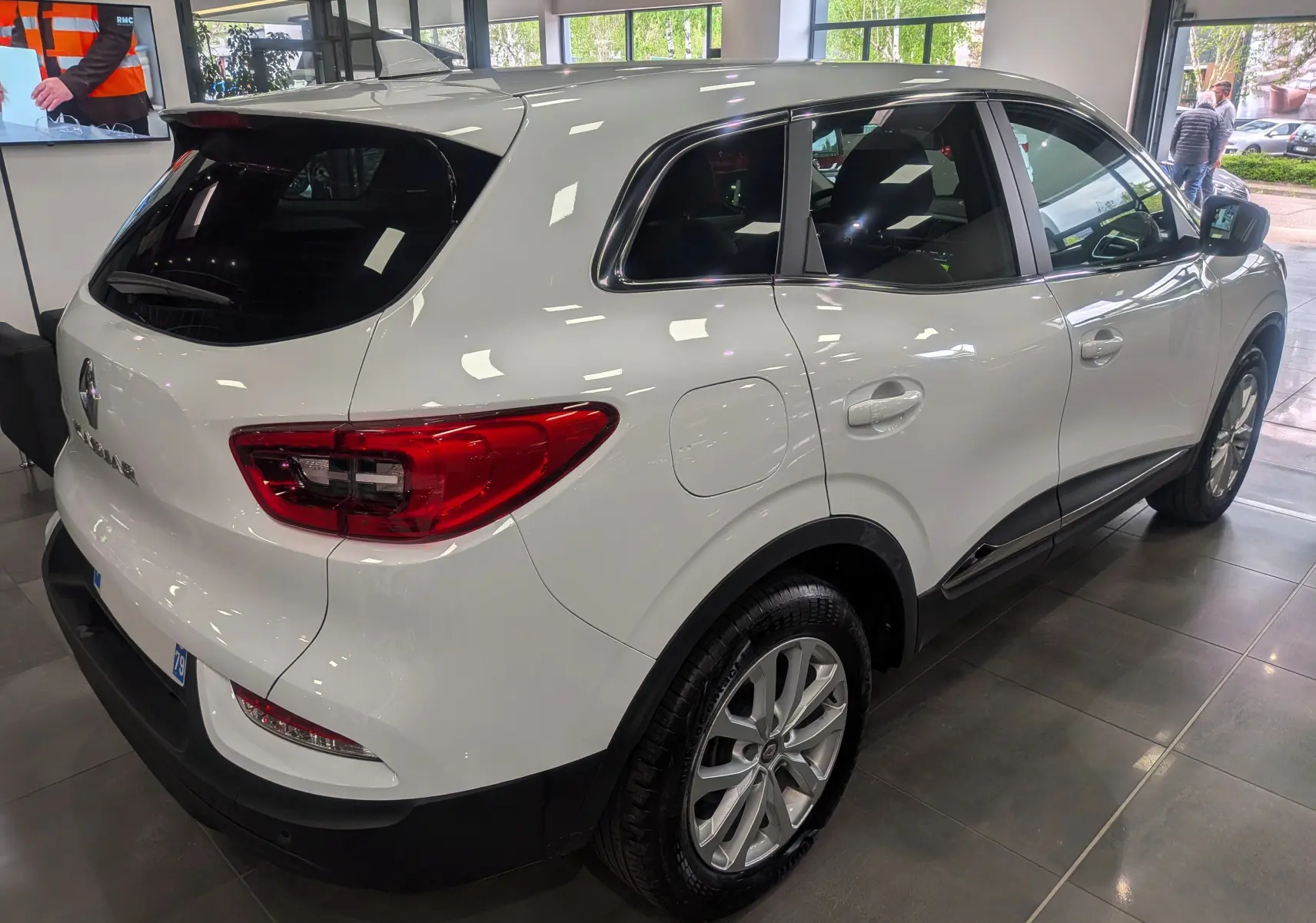 Vue 3/4 arrière droite d'un Renault Kadjar blanc Glacier 2021 en showroom, avec feux arrière rouges et jantes alliage.
