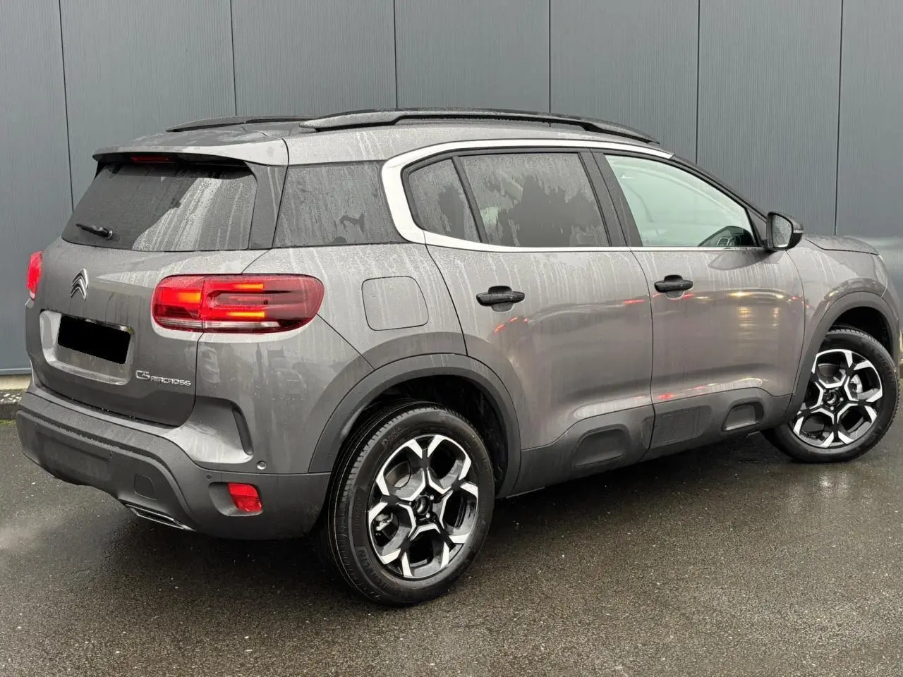 Vue 3/4 arrière droite du Citroën C5 Aircross gris Platinium avec jantes alliage bi-ton et feux arrière LED allumés.