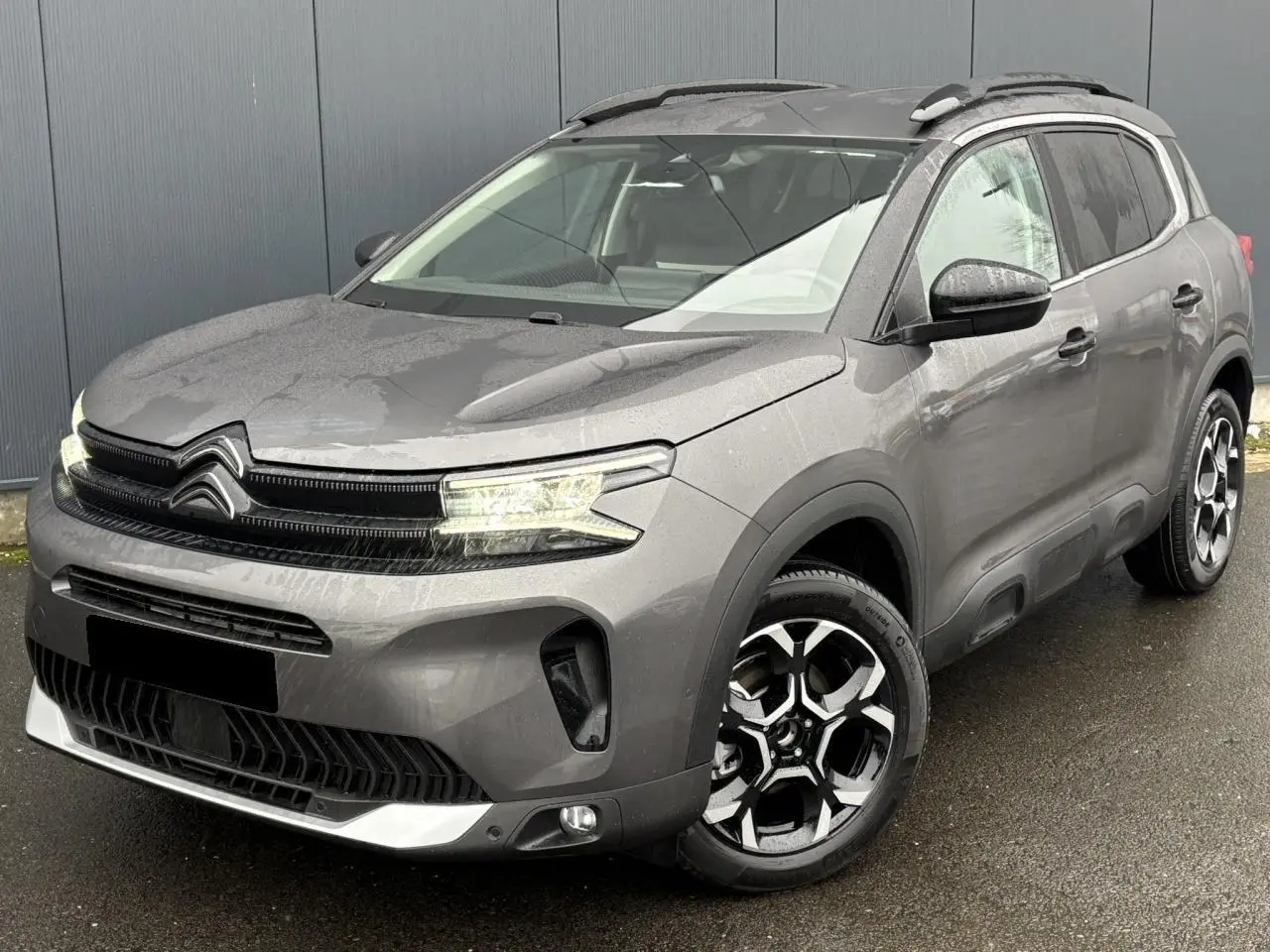 Citroën C5 Aircross gris Platinium en 3/4 avant droit, avec jantes alliage bi-ton et barres de toit noires.
