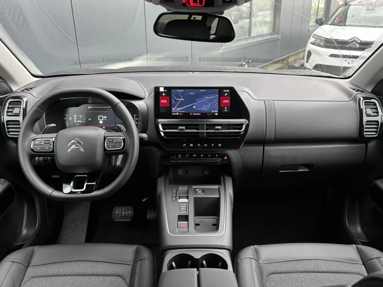 Vue intérieure avant du Citroën C5 Aircross 2025, tableau de bord noir avec écran tactile central et volant multifonction.