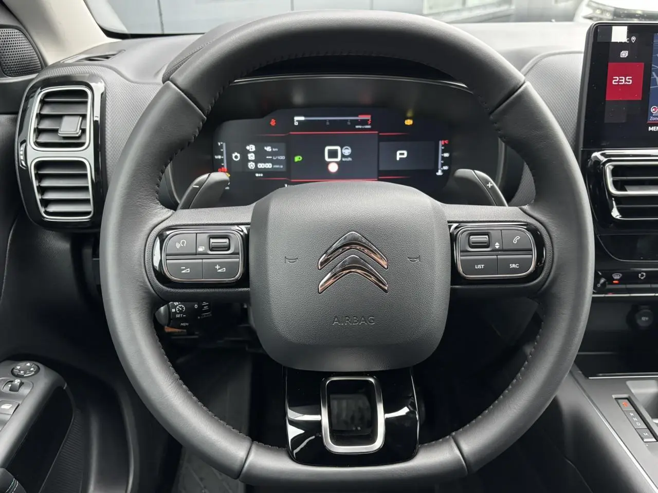 Vue rapprochée du volant cuir noir du Citroën C5 Aircross 2025 avec tableau de bord numérique et commandes intégrées.