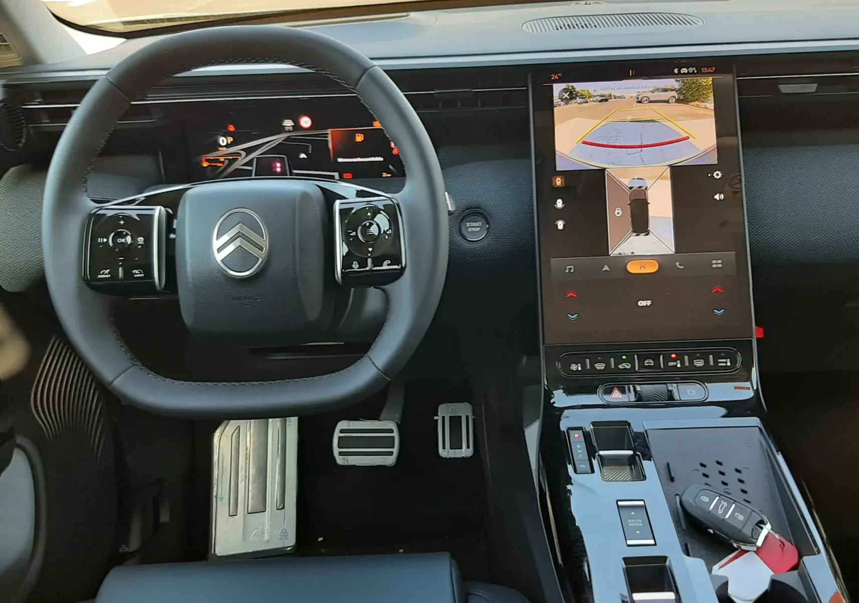 Vue intérieure du poste de conduite du Citroën C5 Aircross hybride 2026, volant noir et écran tactile central allumé.