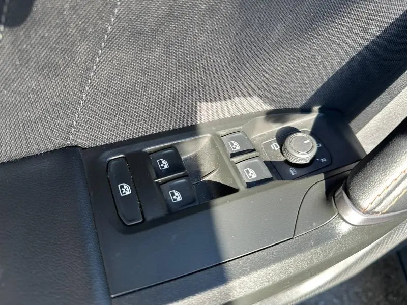 Gros plan sur les commandes des vitres et rétroviseurs côté conducteur d'une CUPRA Formentor bleu, intérieur noir.