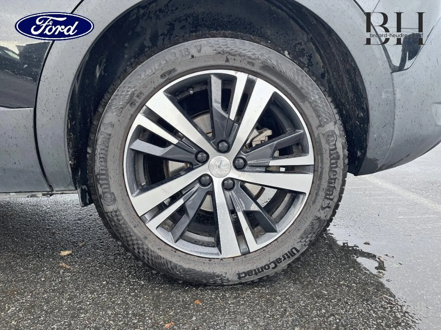 Gros plan sur la roue avant gauche d’un Peugeot 5008 noir Perla Nera avec jante alliage bicolore.