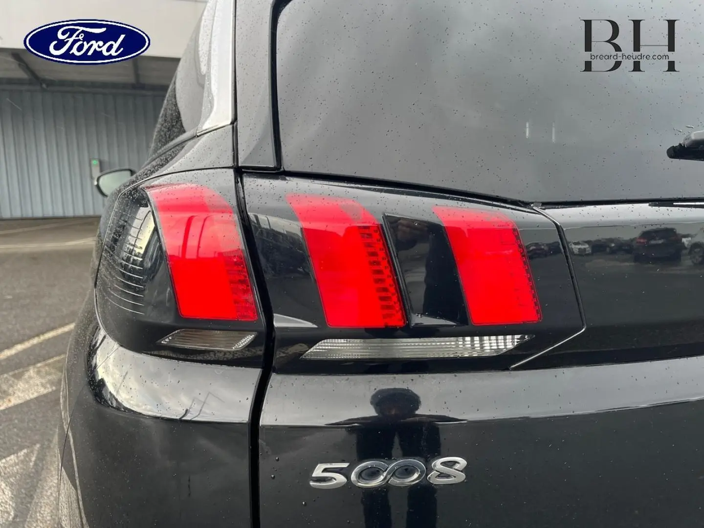 Gros plan sur le feu arrière gauche noir Perla Nera d’un Peugeot 5008 2018 avec logo et reflet sur la carrosserie.