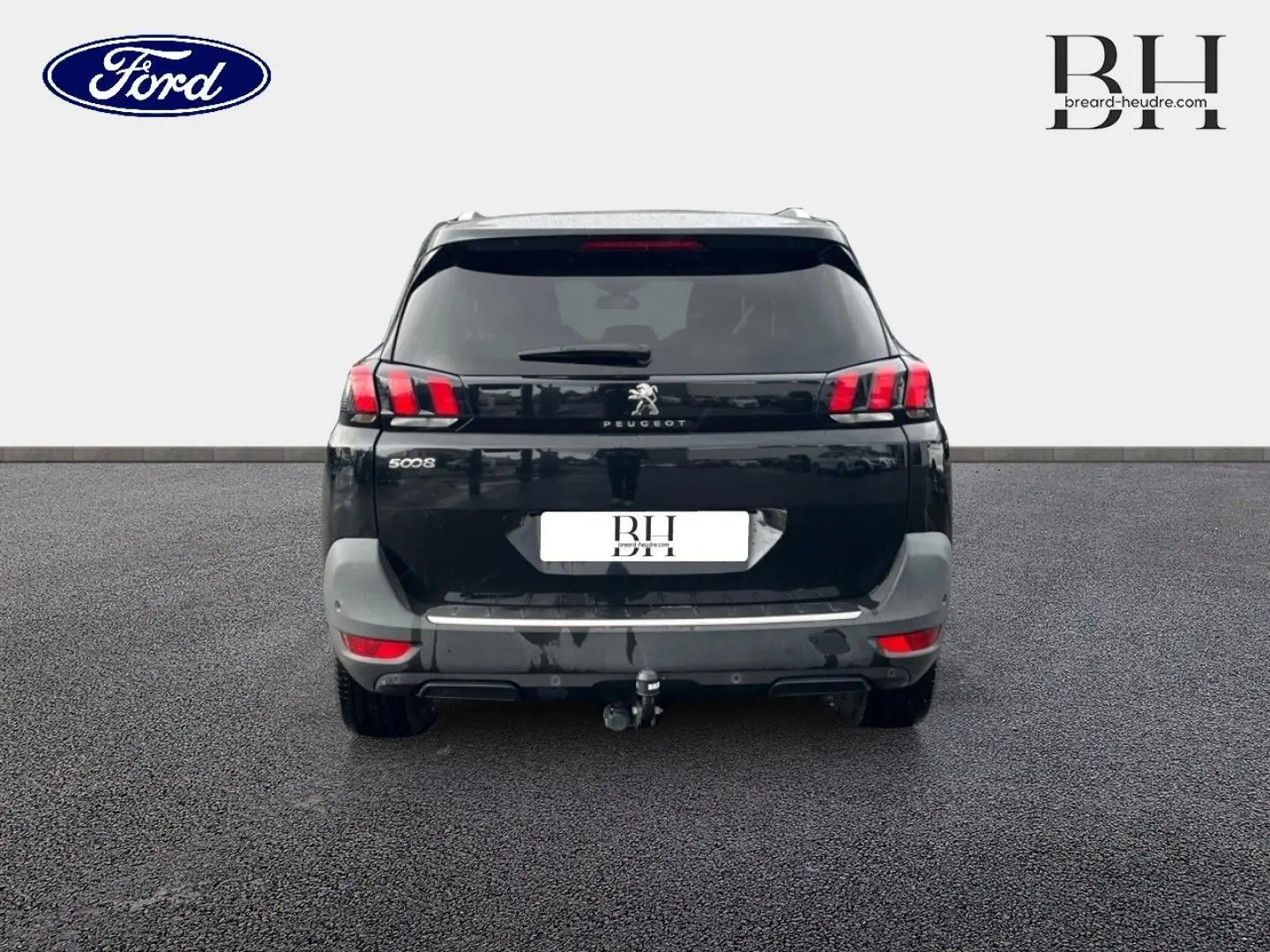 Vue arrière d'un Peugeot 5008 noir Perla Nera avec hayon, feux LED et attelage visible sur sol goudronné.