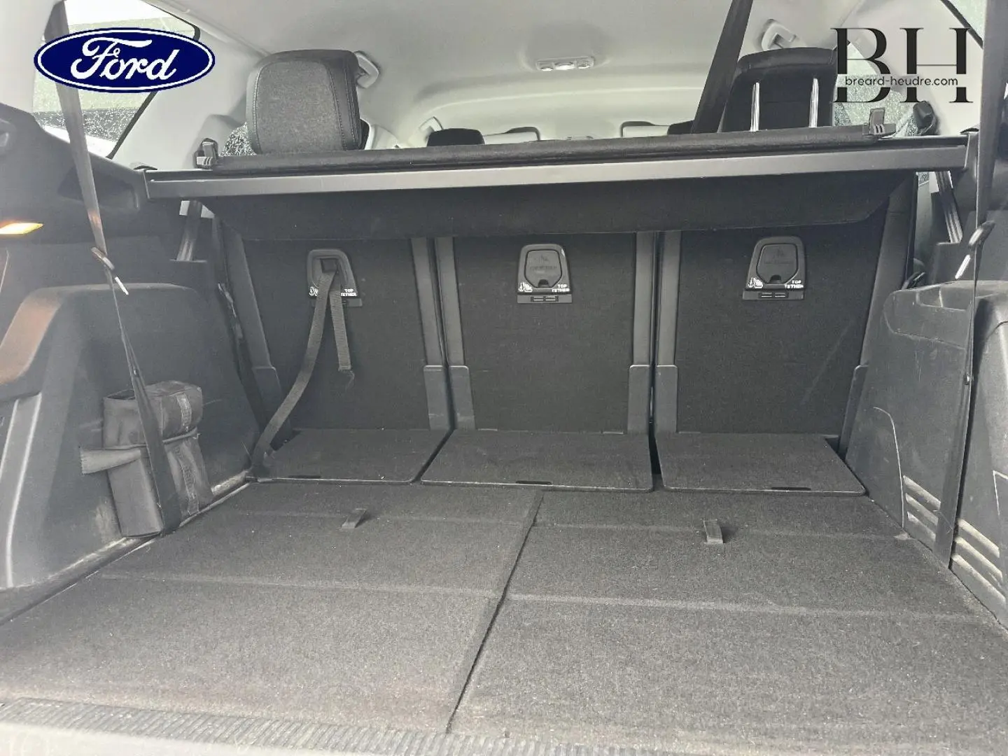 Coffre ouvert d’un SUV noir, vue de l’arrière avec sièges rabattus et banquette arrière visible.