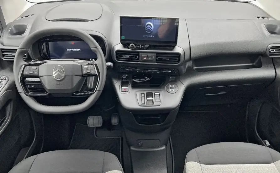 Vue intérieure avant du tableau de bord et du volant noir du Citroën Berlingo Multispace gris, avec écran tactile central allumé.