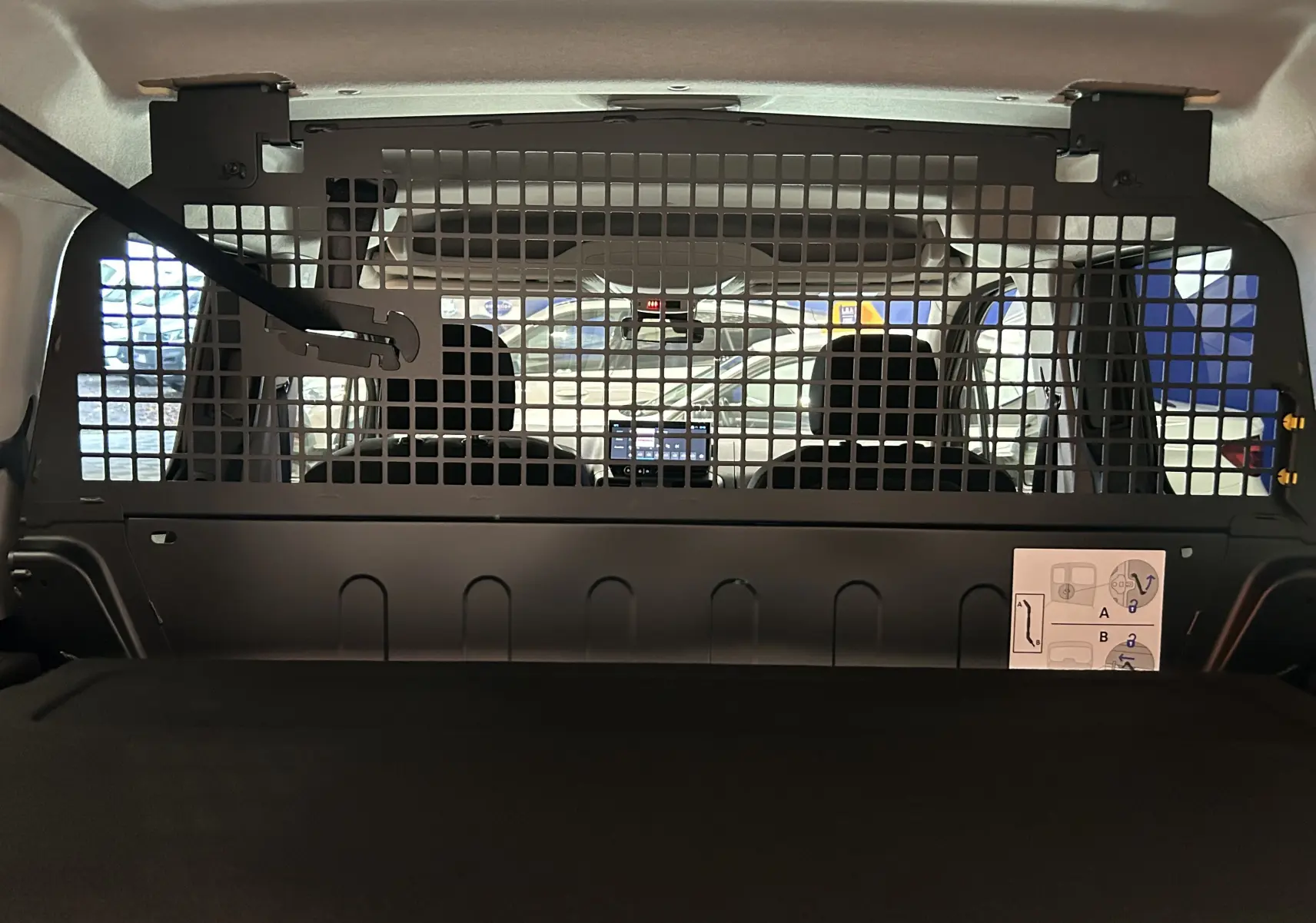 Vue intérieure arrière du Citroën Berlingo Multispace gris Artense, avec séparation grillagée entre coffre et sièges avant.