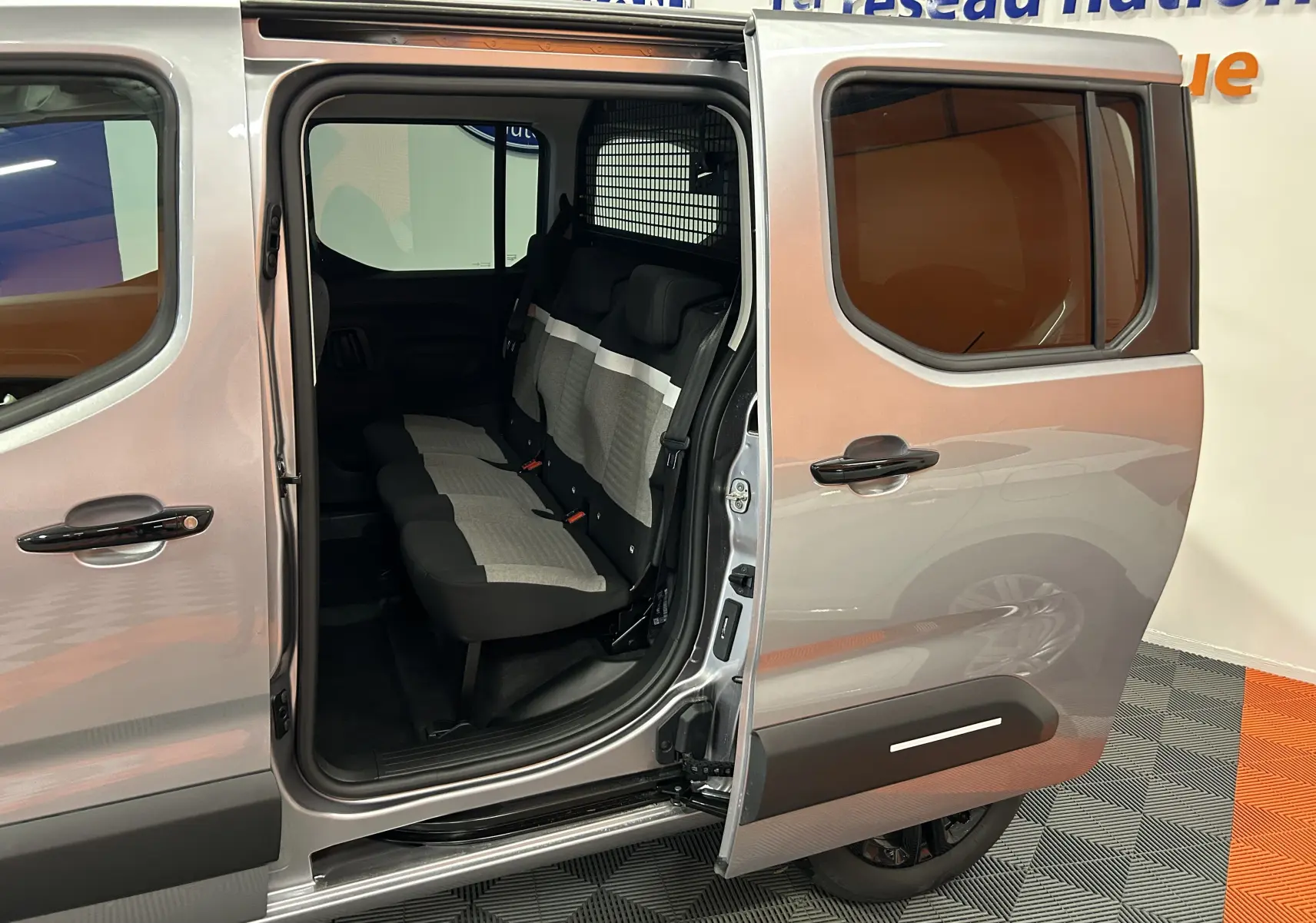 Vue latérale droite du Citroën Berlingo Multispace gris Artense avec porte coulissante ouverte révélant les sièges arrière en tissu bicolore.