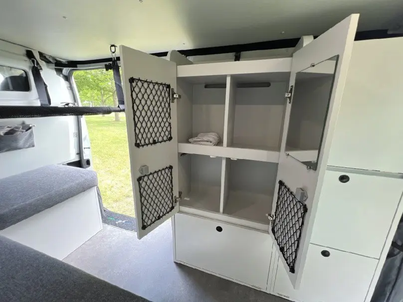 Intérieur du Renault Trafic Fourgon gris 2025, vue sur rangement ouvert avec filet de maintien et banquette côté gauche.