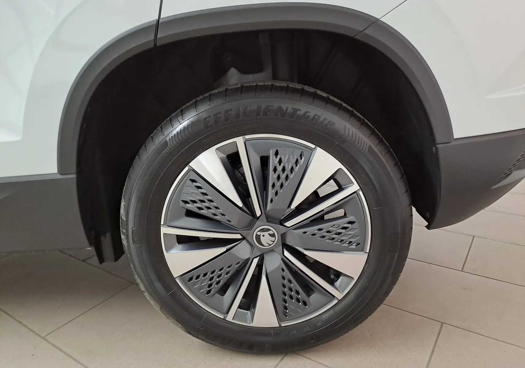 Gros plan sur la roue avant droite du Skoda Karoq blanc Lune, avec jante alliage au design moderne et détails noirs.