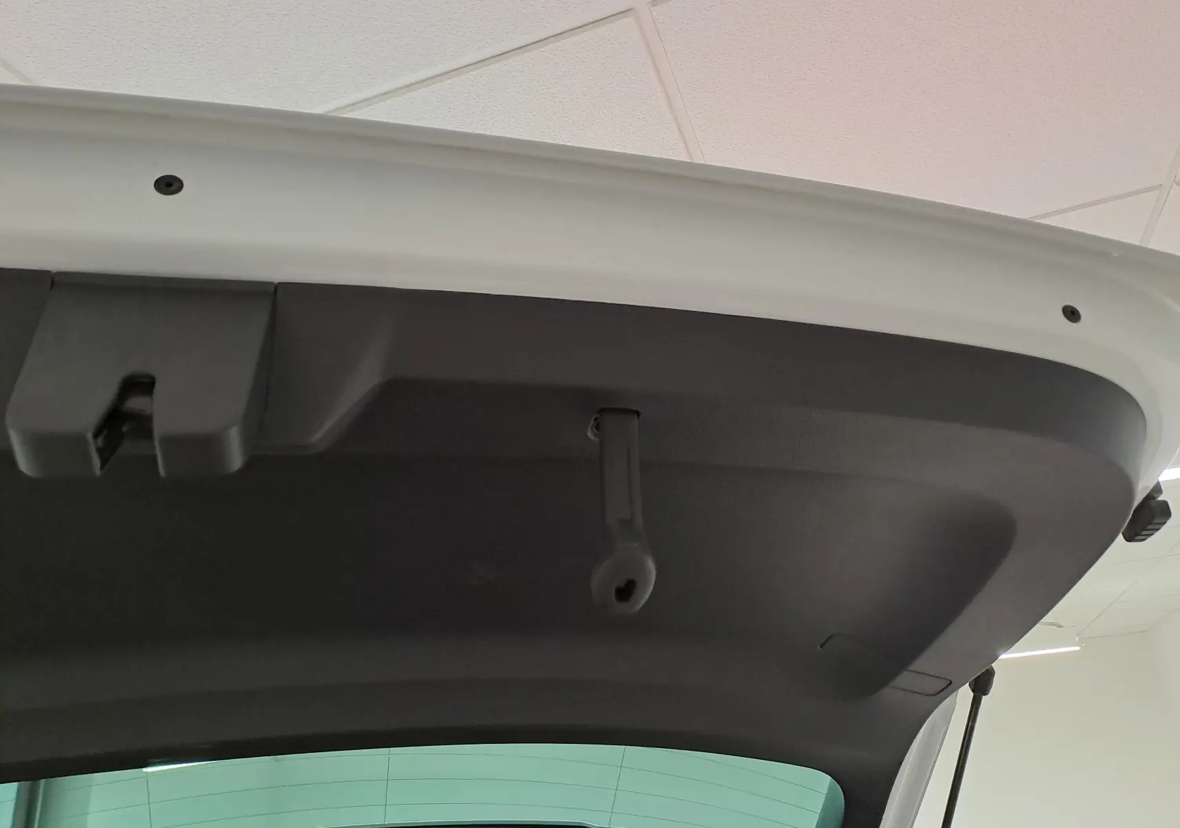 Vue rapprochée de l’intérieur du hayon arrière du Skoda Karoq blanc Lune, montrant la poignée de fermeture noire.