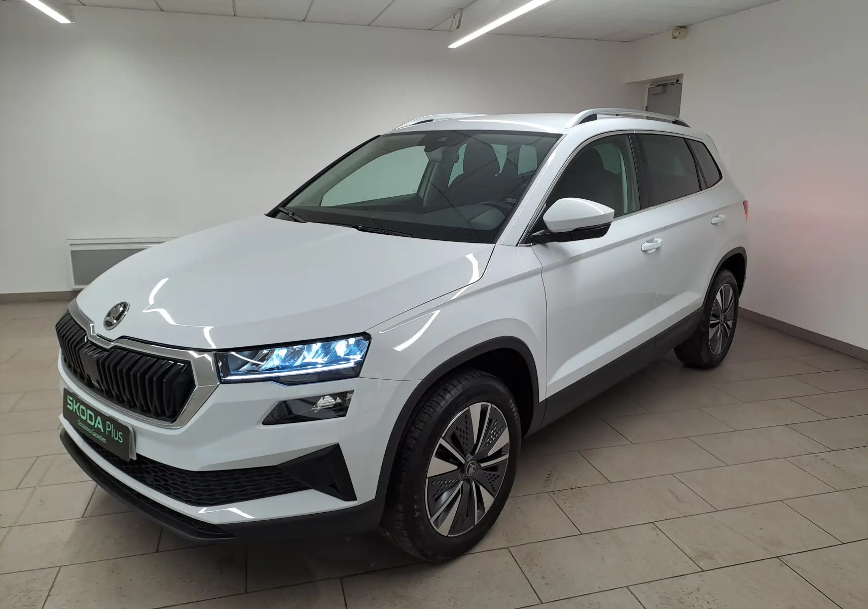 Vue 3/4 avant droite du Skoda Karoq blanc Lune avec calandre noire et jantes spécifiques au Pack Design chrome.