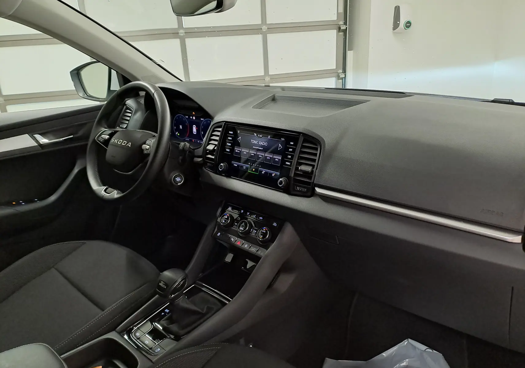 Vue intérieure côté conducteur du Skoda Karoq 2025, tableau de bord noir avec écran tactile et volant multifonction.