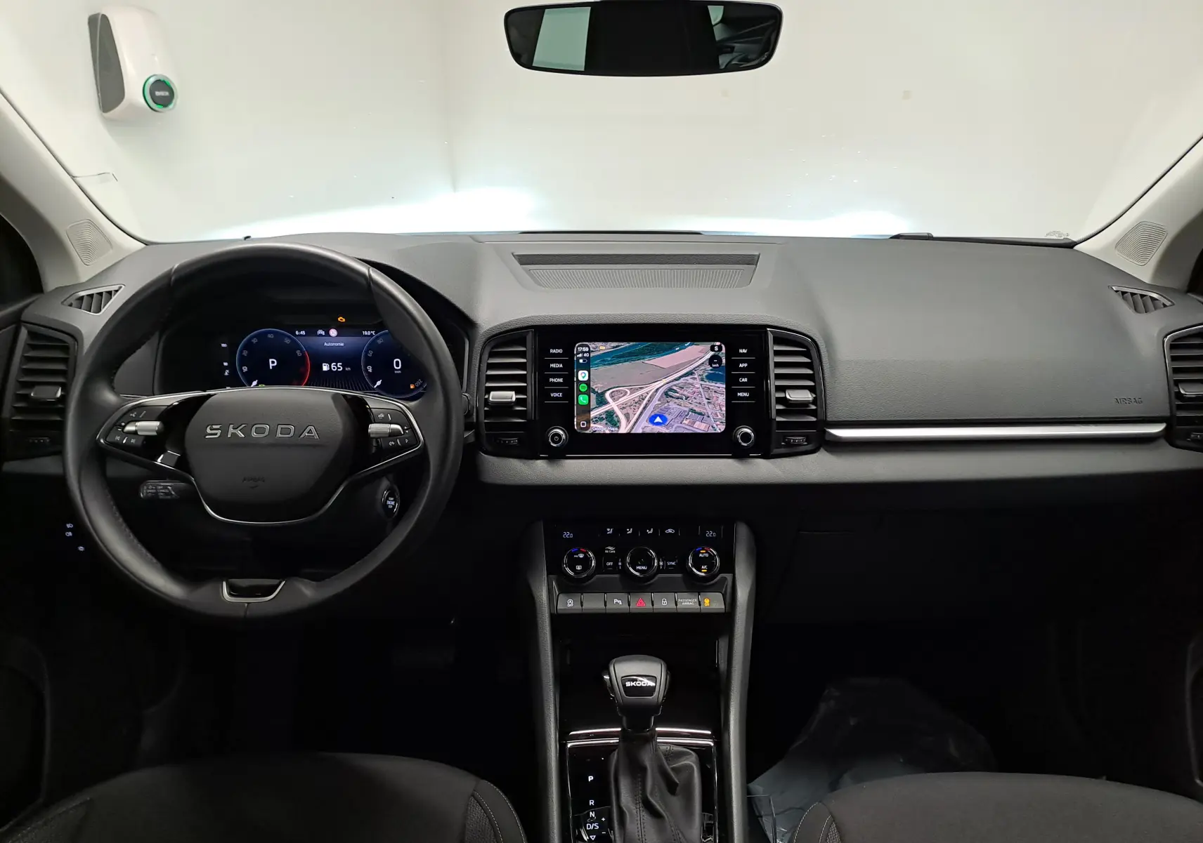 Vue intérieure frontale du Skoda Karoq 2025 avec tableau de bord noir, écran tactile central et volant multifonction.