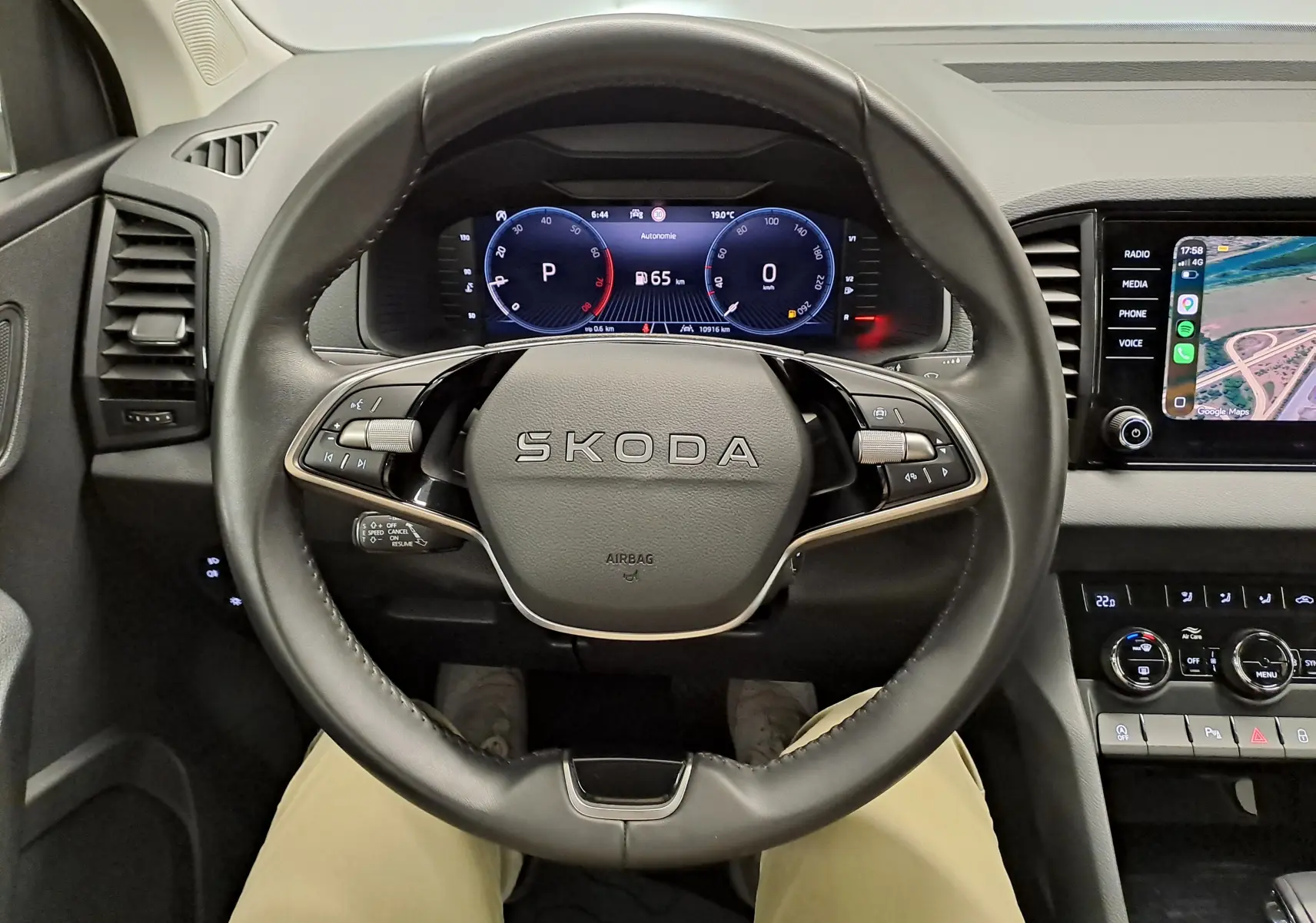 Vue intérieure centrée sur le volant SKODA avec tableau de bord numérique et écran tactile à droite.