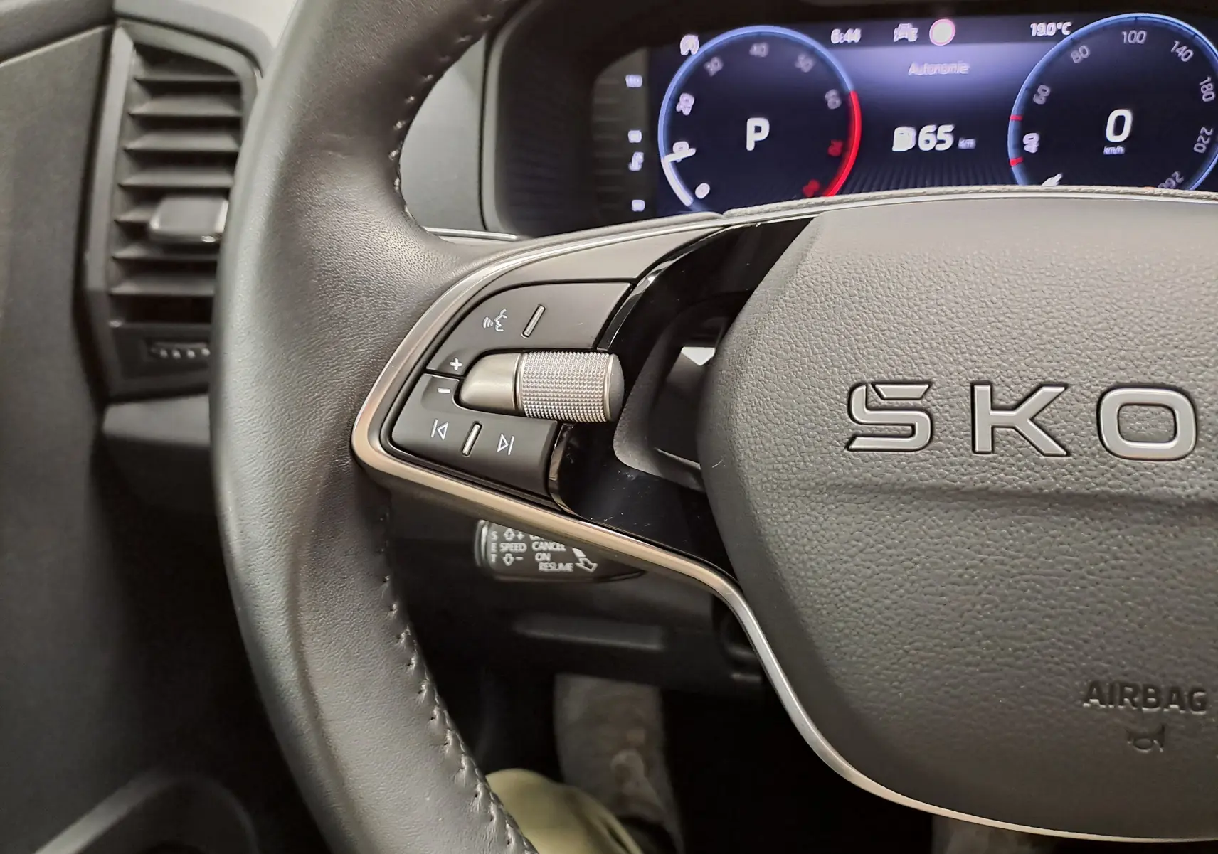 Gros plan sur le volant noir du Skoda Karoq 2025 avec commandes intégrées et tableau de bord numérique en arrière-plan.