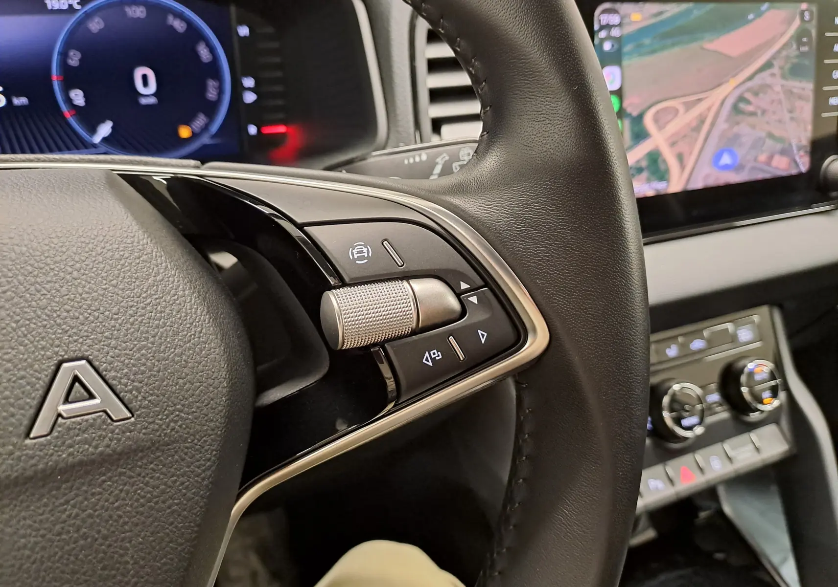 Gros plan sur le volant noir du Skoda Karoq 2025 avec commandes intégrées et écran de navigation visible en arrière-plan.
