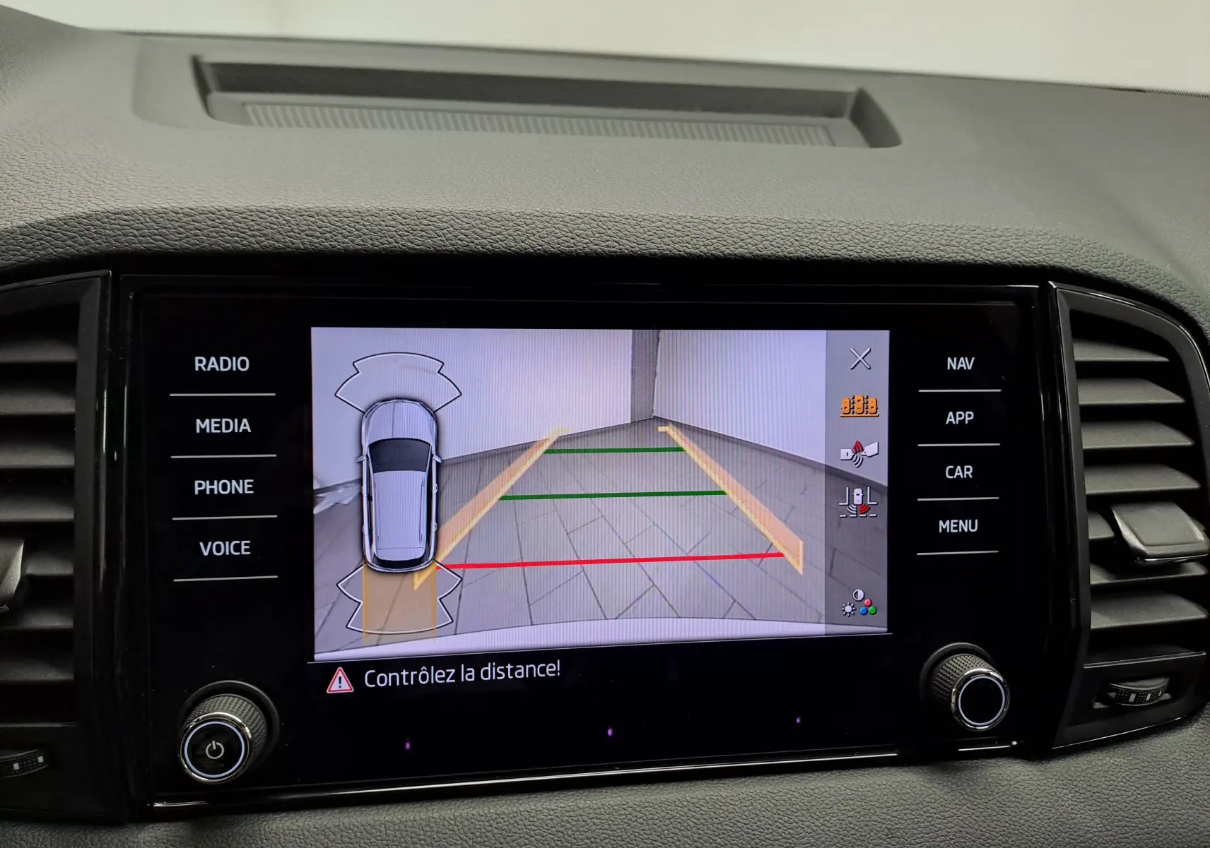Écran multimédia du Skoda Karoq blanc Lune montrant la caméra de recul avec guidage de trajectoire et alertes de distance.