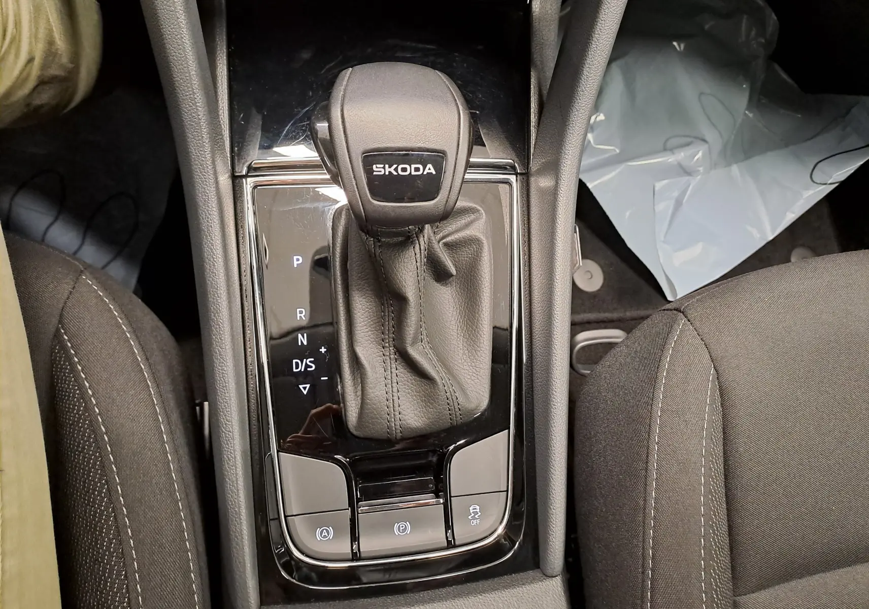 Le levier de vitesses automatique SKODA au centre de la console, entouré de sièges en tissu noir.