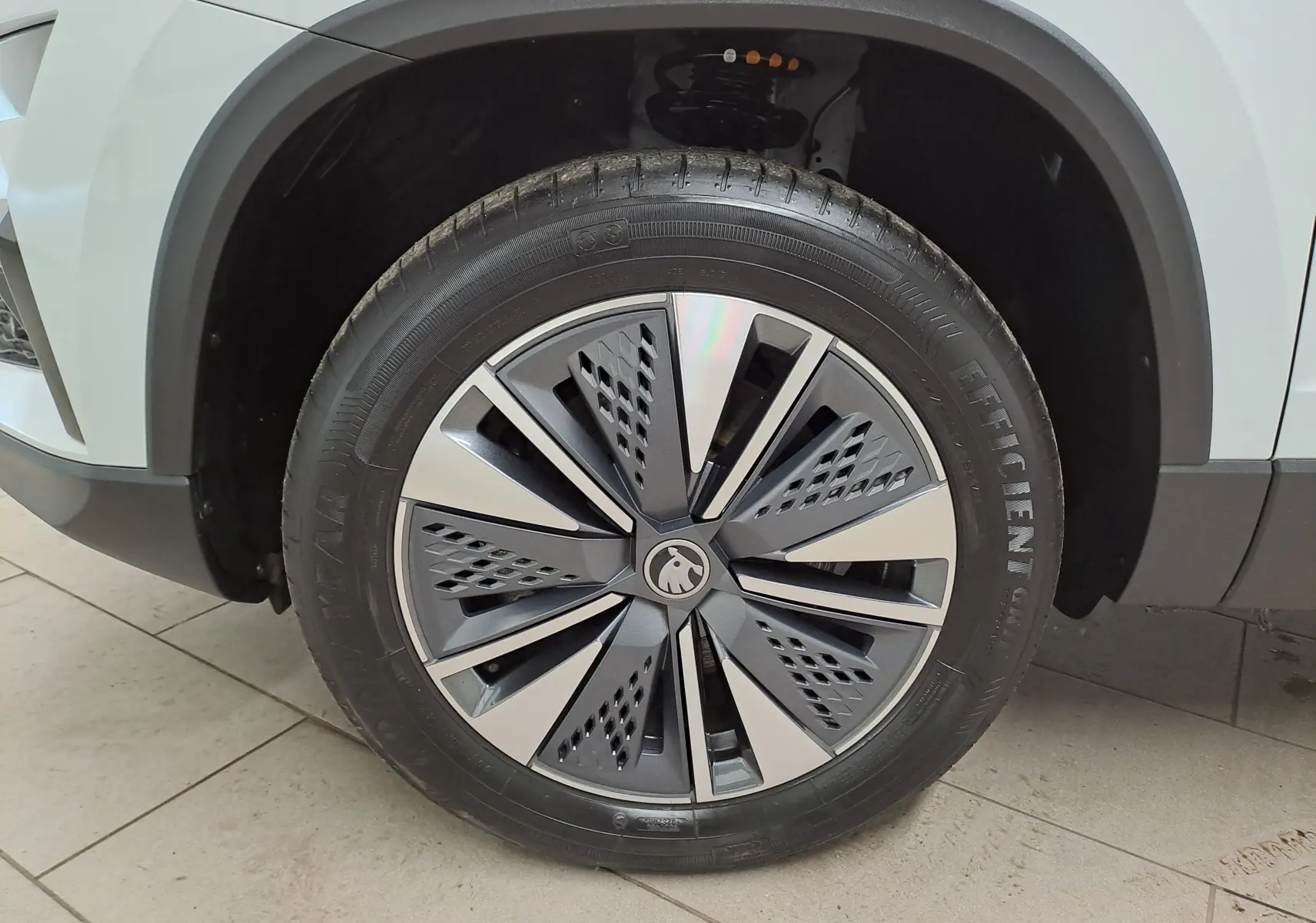 Gros plan sur la roue avant gauche du Skoda Karoq blanc Lune, mettant en valeur la jante au design moderne bicolore.