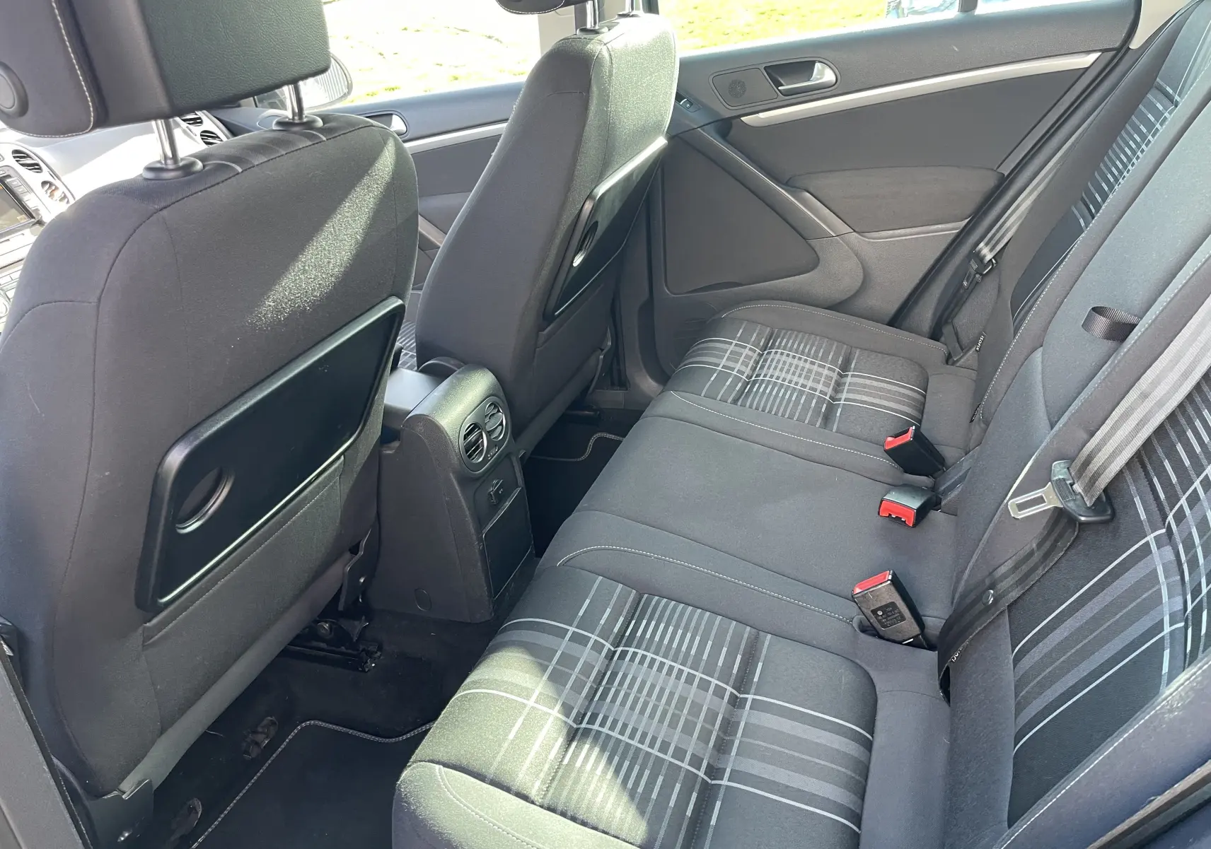 Vue intérieure arrière côté droit du Volkswagen Tiguan 2015 gris foncé, montrant les sièges arrière avec motifs à carreaux et appuie-têtes.