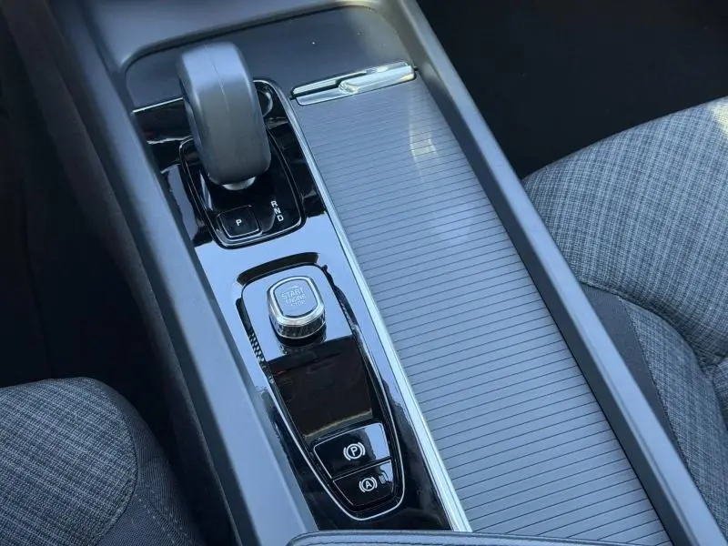 Vue rapprochée de la console centrale noire brillante du Volvo XC60 gris avec levier de vitesse et bouton start/stop.