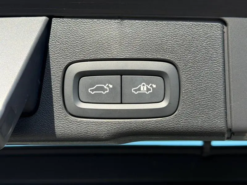 Gros plan sur les boutons gris d'ouverture et verrouillage électrique du coffre du Volvo XC60 T6 AWD 2024.