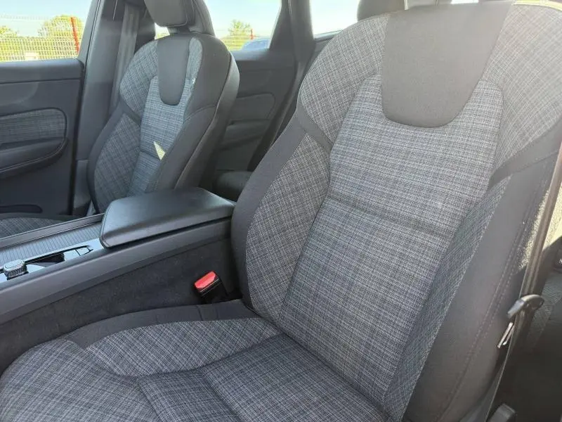 Vue rapprochée des sièges avant en tissu gris à motif tartan du Volvo XC60 T6 AWD 2024 avec accoudoir central noir.