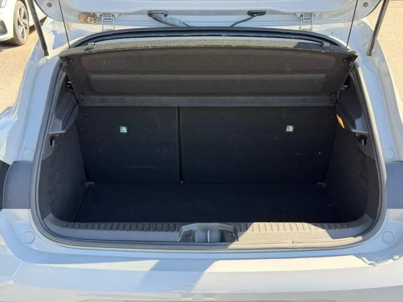Coffre ouvert vu de l'arrière d'une Renault Clio 1.5 dCi 100ch Evolution gris Rafale, intérieur noir et espace de chargement vide.