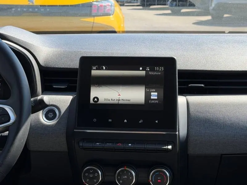Vue intérieure centrée sur l'écran tactile et la console d'une Renault Clio 1.5 dCi 2025 gris Rafale, volant partiel visible.