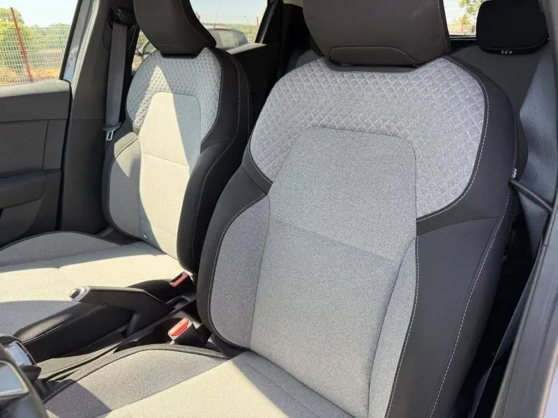 Vue rapprochée des sièges avant gris clair et noir de la Renault Clio 1.5 dCi 2025, avec motif 3D sur dossier.