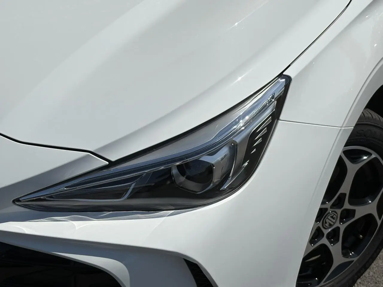 Gros plan sur le phare avant droit blanc Dover du MG3 1.5 Hybrid+ 195 Comfort avec jante alliage 16 pouces.