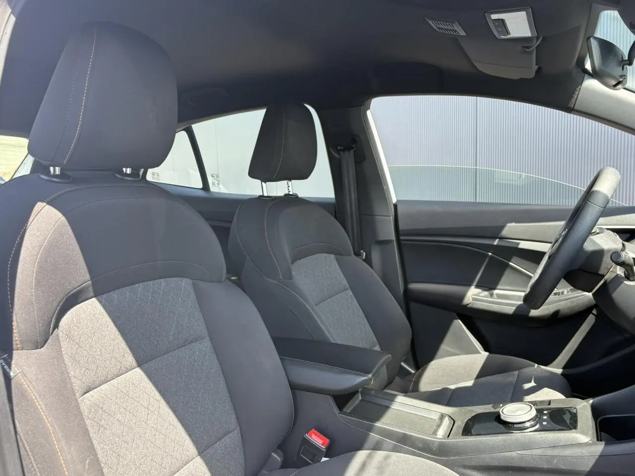 Vue intérieure côté droit du MG3 1.5 Hybrid+ 195 Comfort avec sièges tissu noir et accoudoir central.