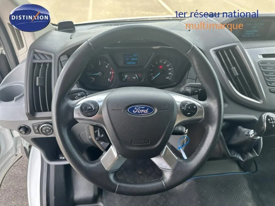 Vue intérieure centrée sur le volant noir du Ford Transit Fourgon blanc, avec levier de vitesses manuel visible à droite.