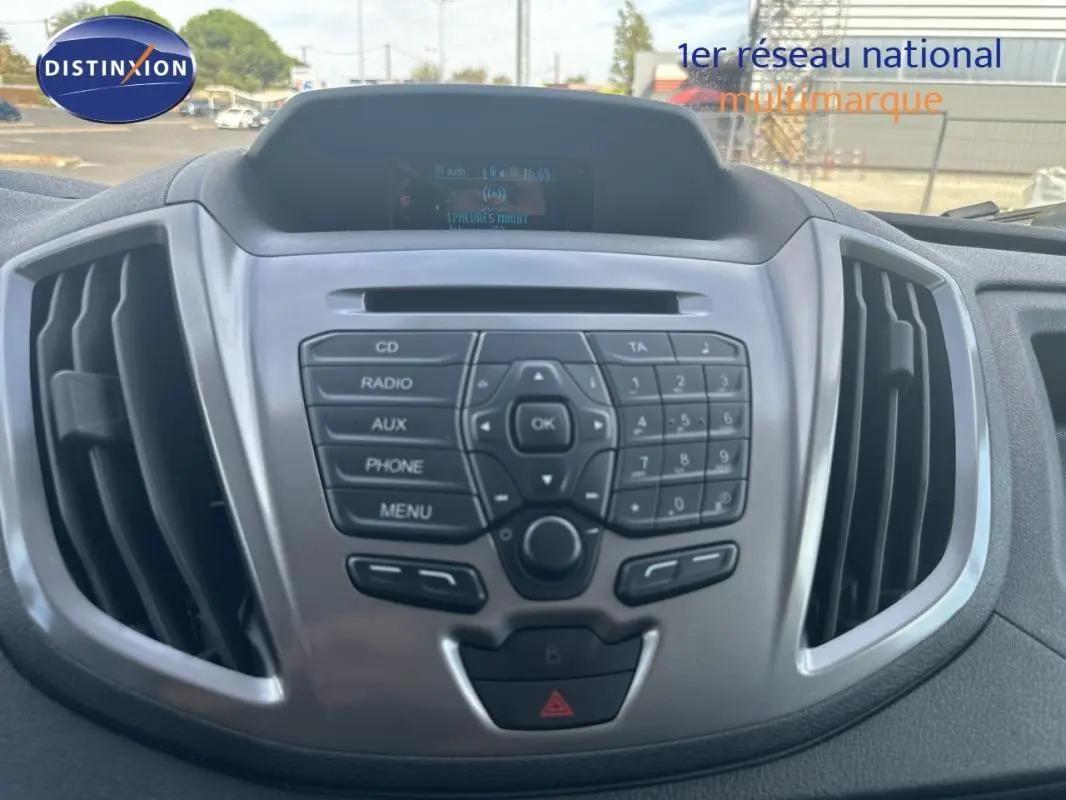 Vue rapprochée du tableau de bord gris du Ford Transit Fourgon blanc, mettant en valeur la console centrale avec commandes audio.