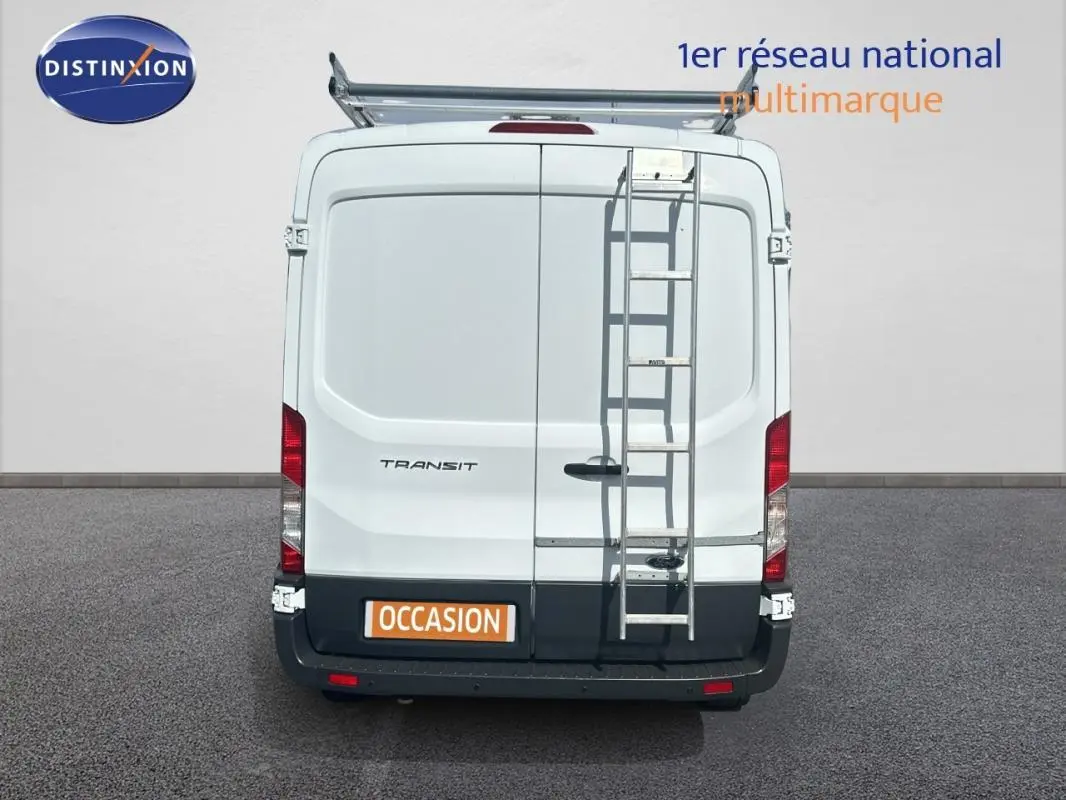 Vue arrière d’un Ford Transit Fourgon blanc 2015 avec échelle métallique fixée et porte latérale visible.