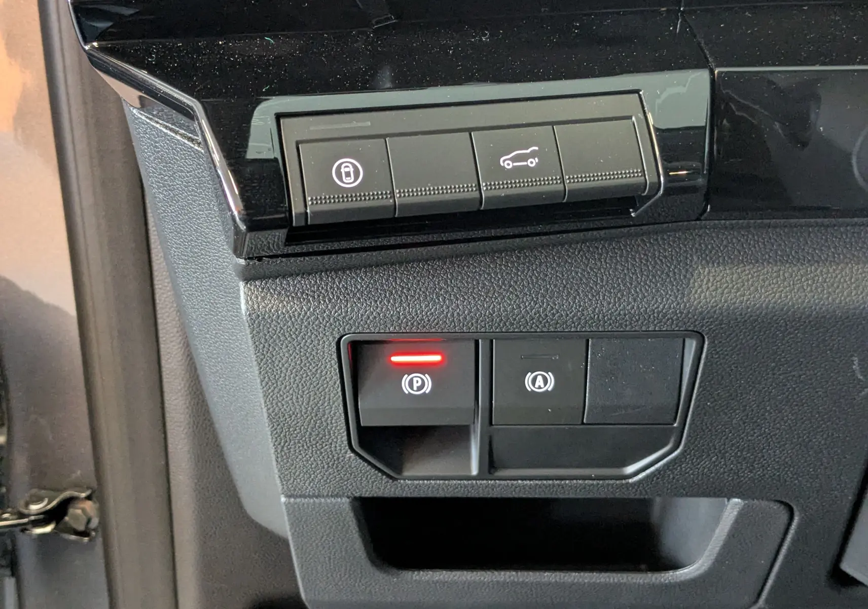 Boutons de commande du hayon motorisé et frein à main électronique sur tableau de bord noir du Renault Austral gris schist 2025.