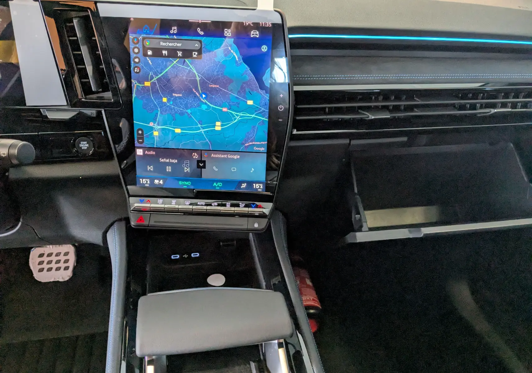 Vue intérieure du tableau de bord du Renault Austral e-tech, avec écran tactile central affichant une carte et boîte à gants ouverte.