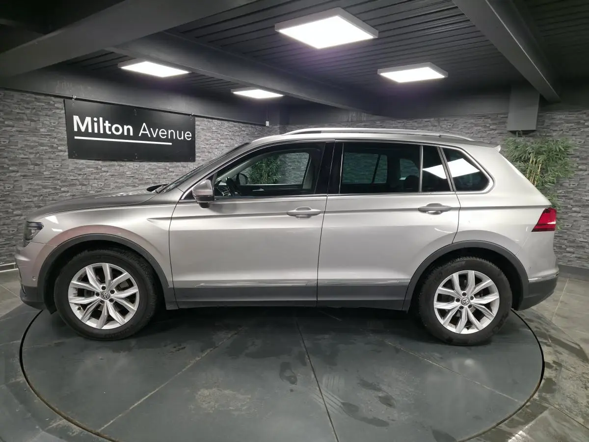 Volkswagen Tiguan gris métallisé vu de profil côté gauche dans un showroom avec jantes alliage 18 pouces.