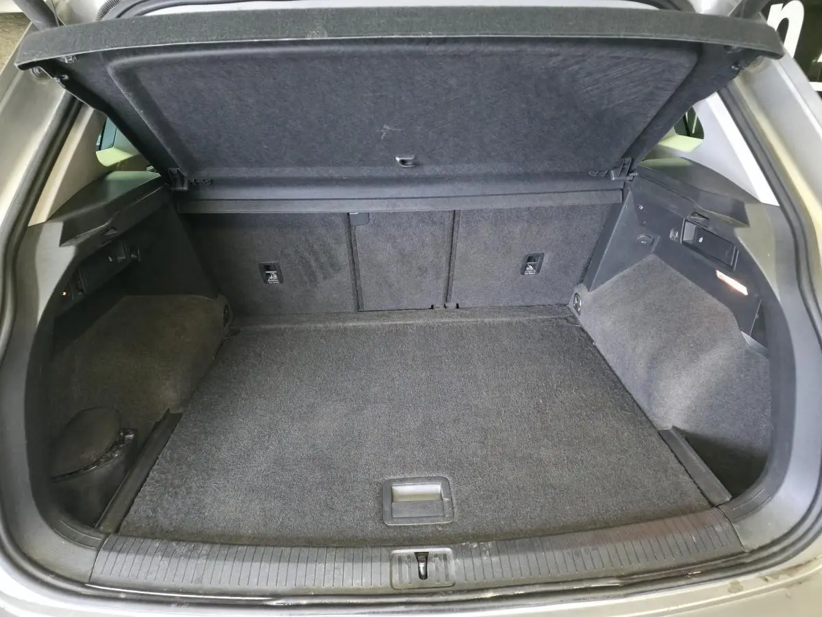 Coffre ouvert du Volkswagen Tiguan gris 2020, montrant un plancher modulable et un espace de rangement spacieux.