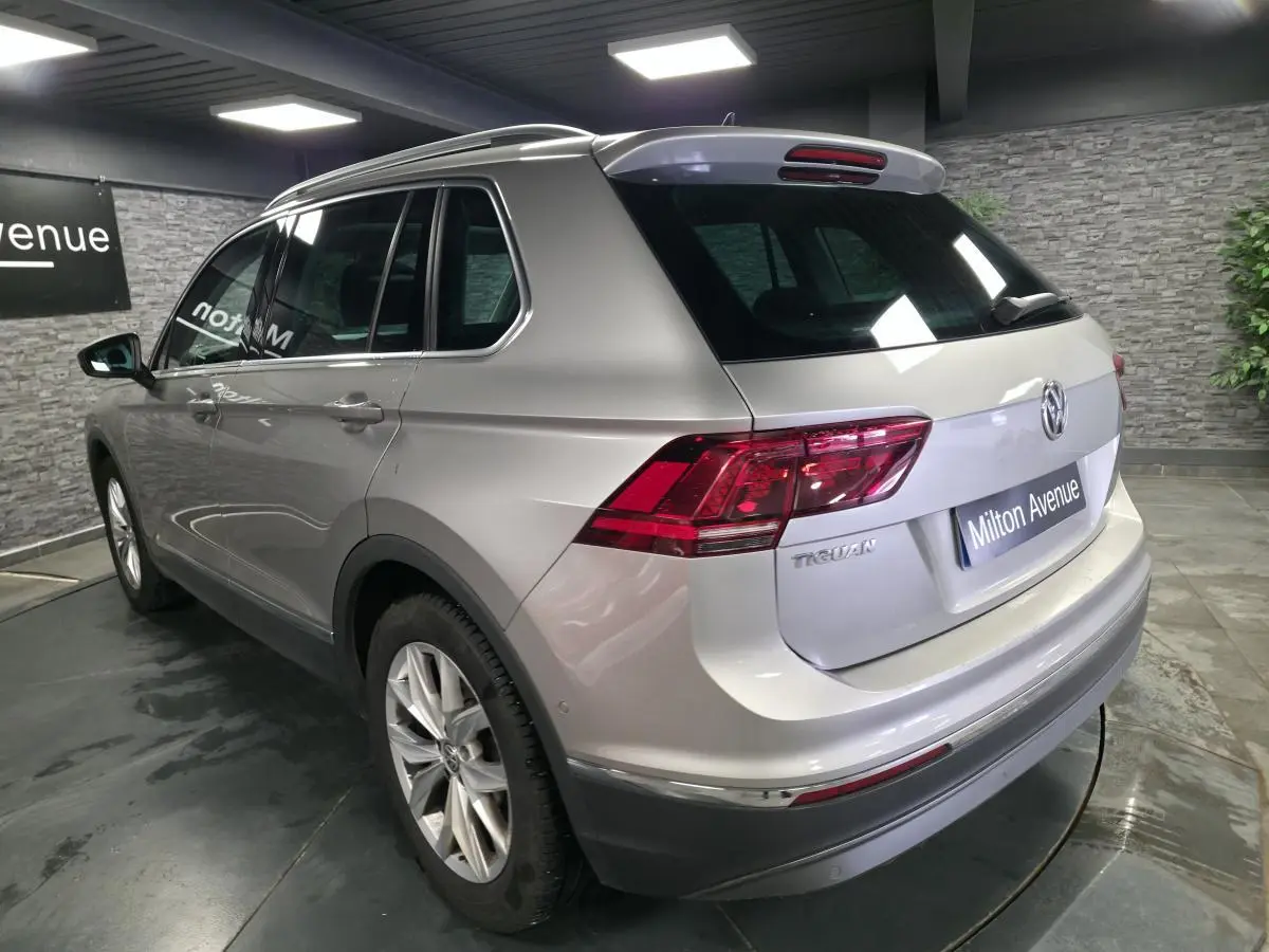 Volkswagen Tiguan gris métallisé vu en 3/4 arrière droit avec feux arrière LED et jantes alliage 18 pouces.