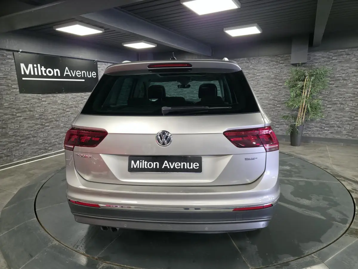 Vue arrière d'un Volkswagen Tiguan gris métallisé 2020 avec feux LED et logo VW bien visibles dans un showroom.